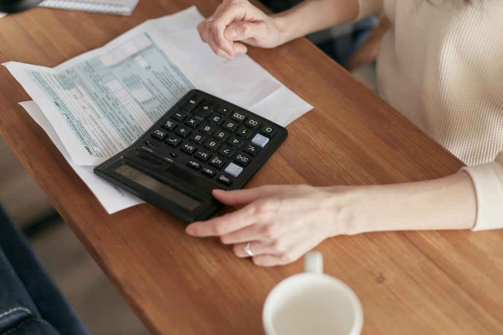 A serene desk scene featuring a calculator, notepad, and a laptop displaying financial graphs, surrounded by potted plants and a cup of coffee, emphasizing a calm and organized atmosphere for debt management. Investing and money management.